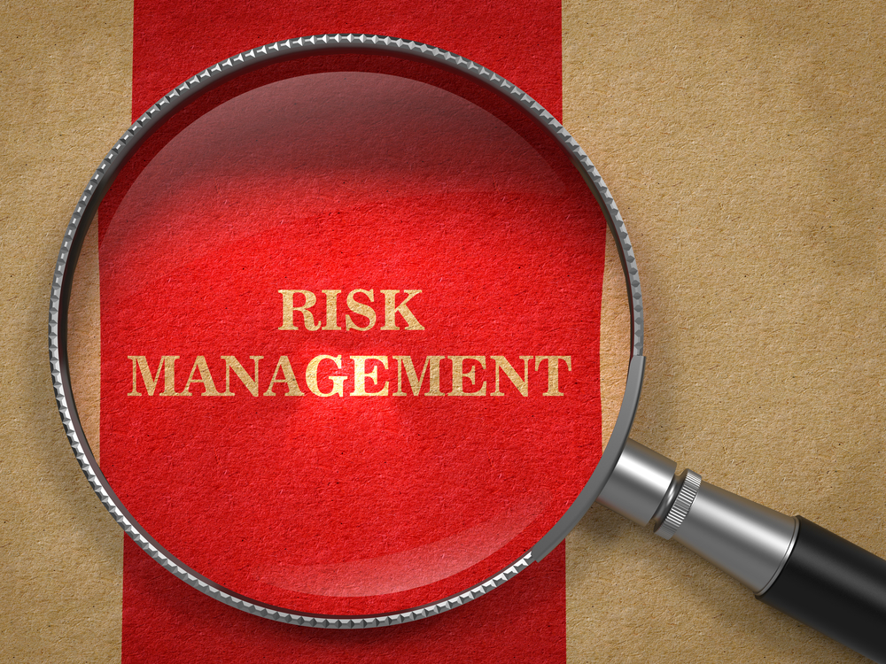 Risk Management Concept. Magnifying Glass on Old Paper with Red Vertical Line Background.